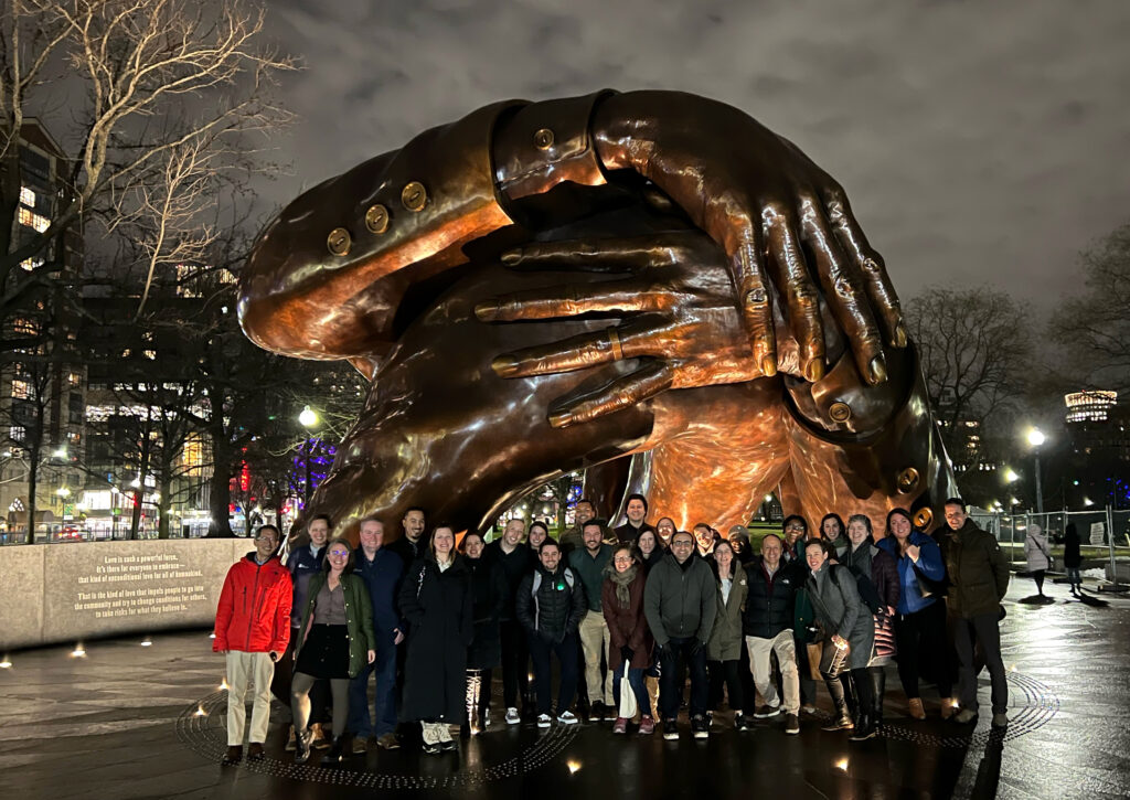 Barr staff members gather in front of the Embrace artwork at night